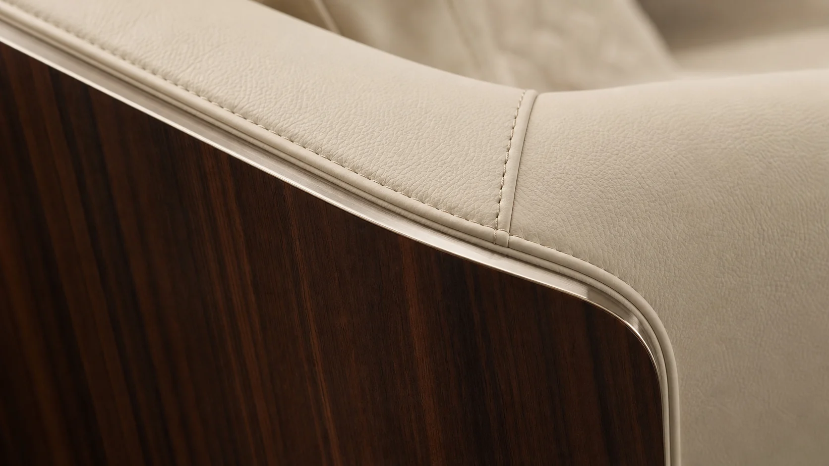 Macro concept showing ivory upholstery stitching, walnut surface and champagne metal trim